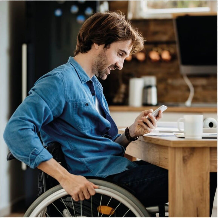 Hombre en silla de ruedas disfrutando de una taza de café en una vivienda accesible.